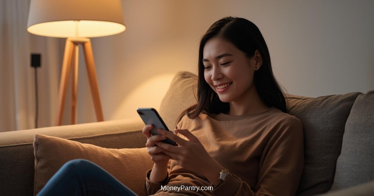 Woman smiling while texting on a smartphone at home, representing companionship texting platforms like Phrendly