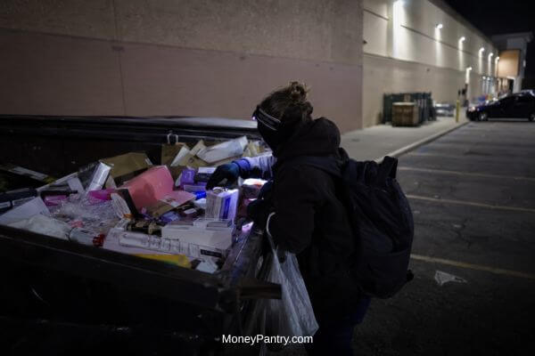 Sorting Sealed Drugstore Items After Dumpster Diving - MoneyPantry.com Person sorting sealed drugstore items found while dumpster diving on a driveway at night.