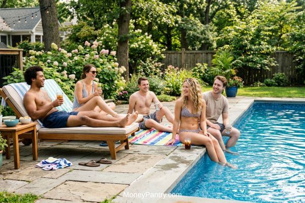 Friends relaxing together at a rented backyard pool during a sunny afternoon party.